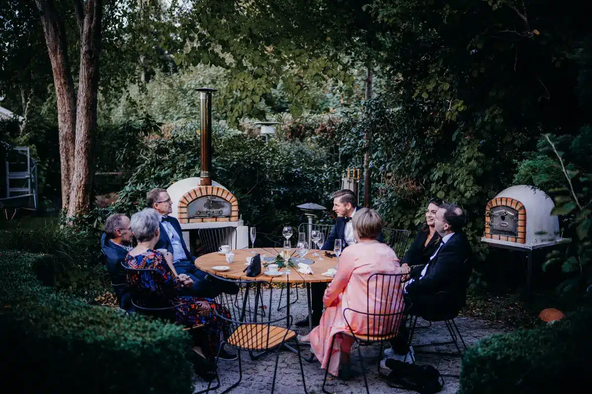 Tavolo in cucina rustica al tramonto con bicchieri di vino e carte da gioco, ospiti in arrivo sullo sfondo