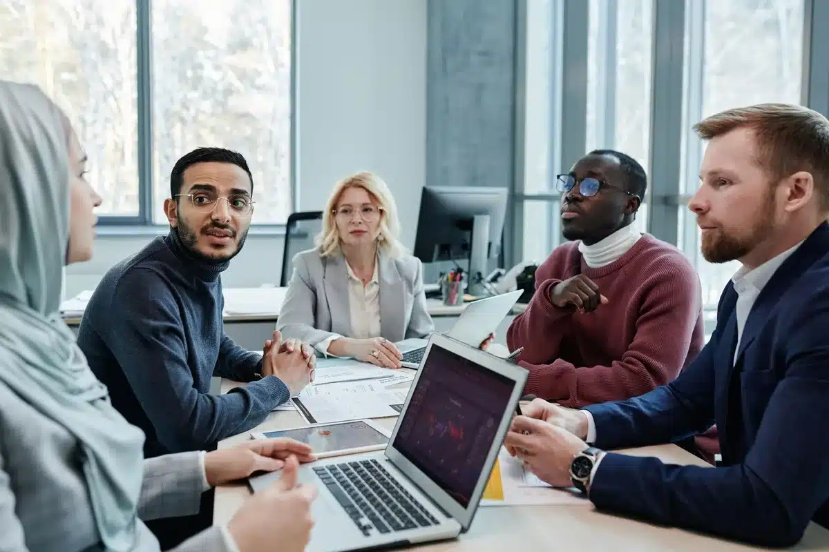 Dipendenti di diversa abilità collaborano insieme in ufficio attorno a un tavolo di riunione