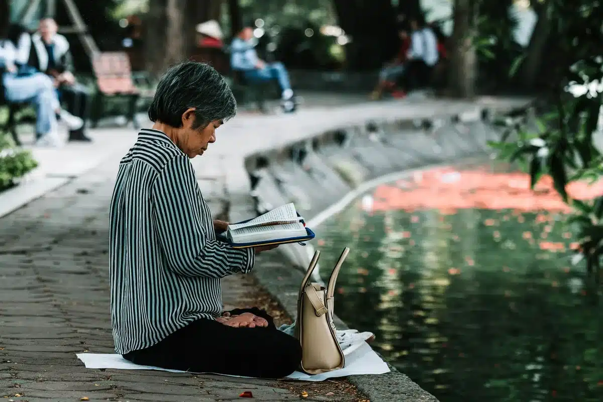 Persona che legge un libro in un ambiente naturale sereno, lontano da dispositivi tecnologici