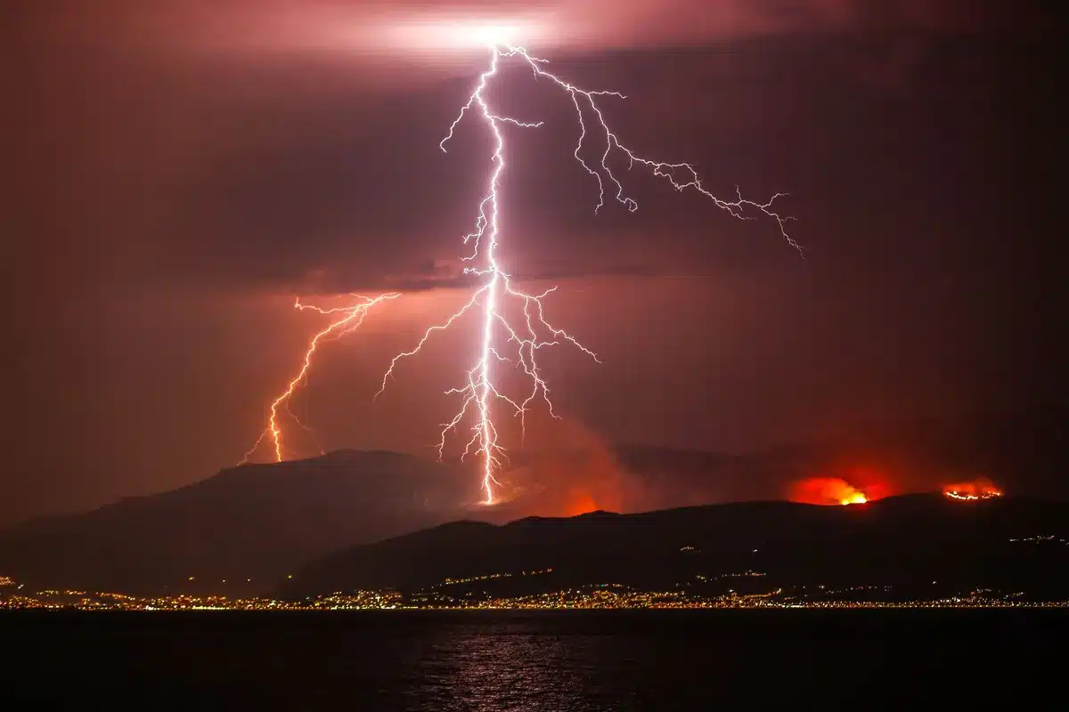 Colonna di fumo da incendio boschivo con fulmine e tempesta al suo interno
