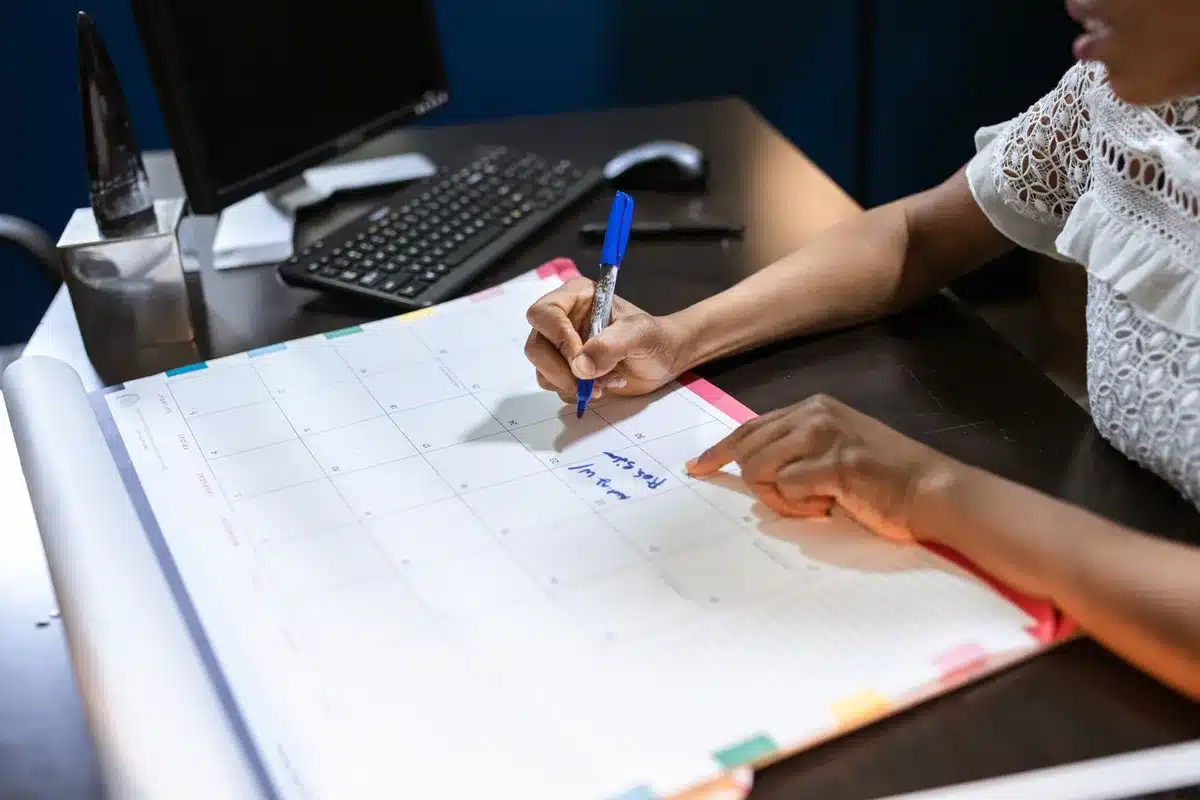 Scrivania d'ufficio con documenti e calendario, mano che raggiunge il telefono