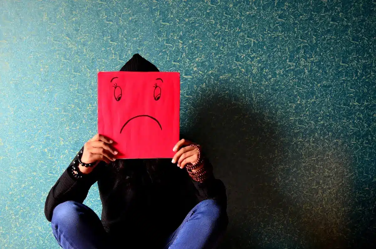 Persona in ansia seduta davanti a schermi digitali, simbolo di stress legale e molestie online.