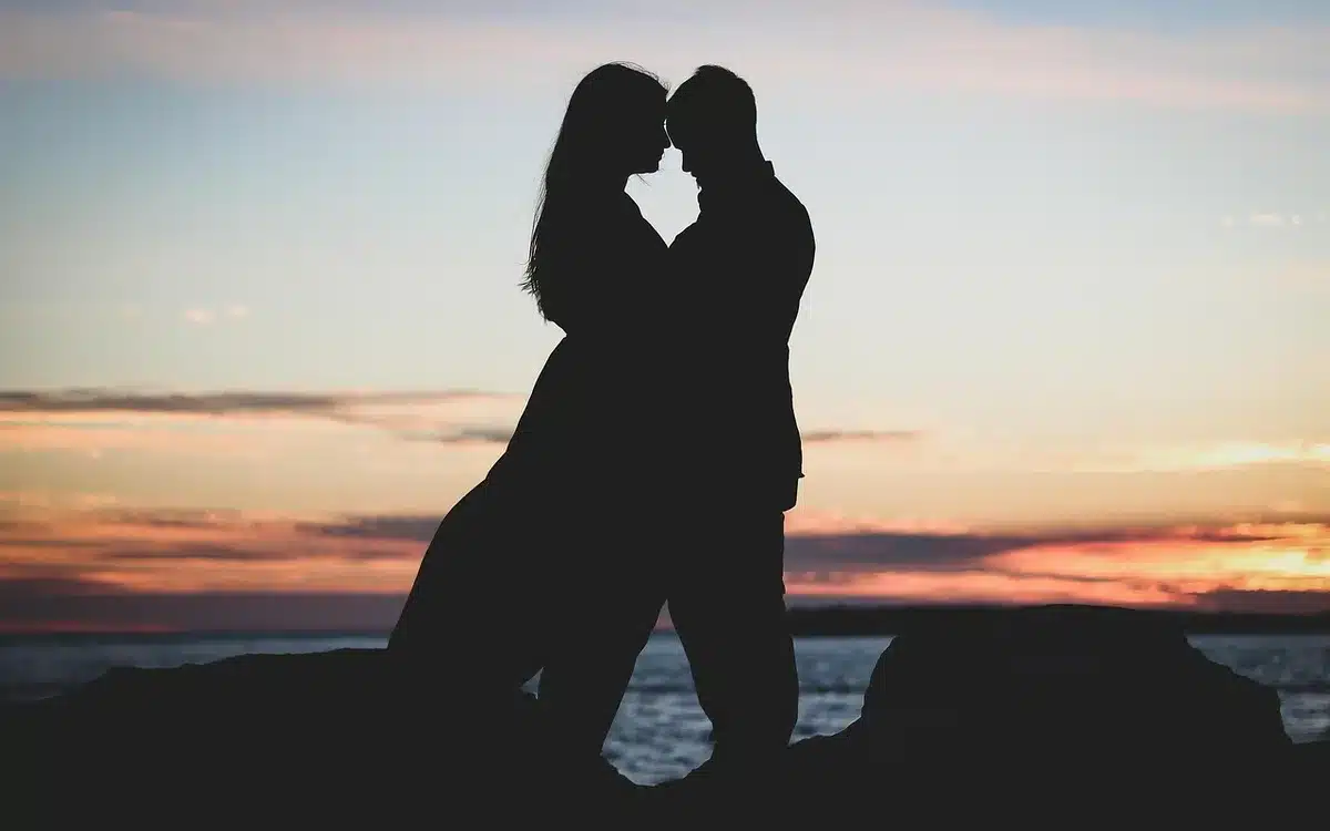 Silhouette di una coppia che cammina tra vigneti toscani al tramonto con tavolo apparecchiato sullo sfondo