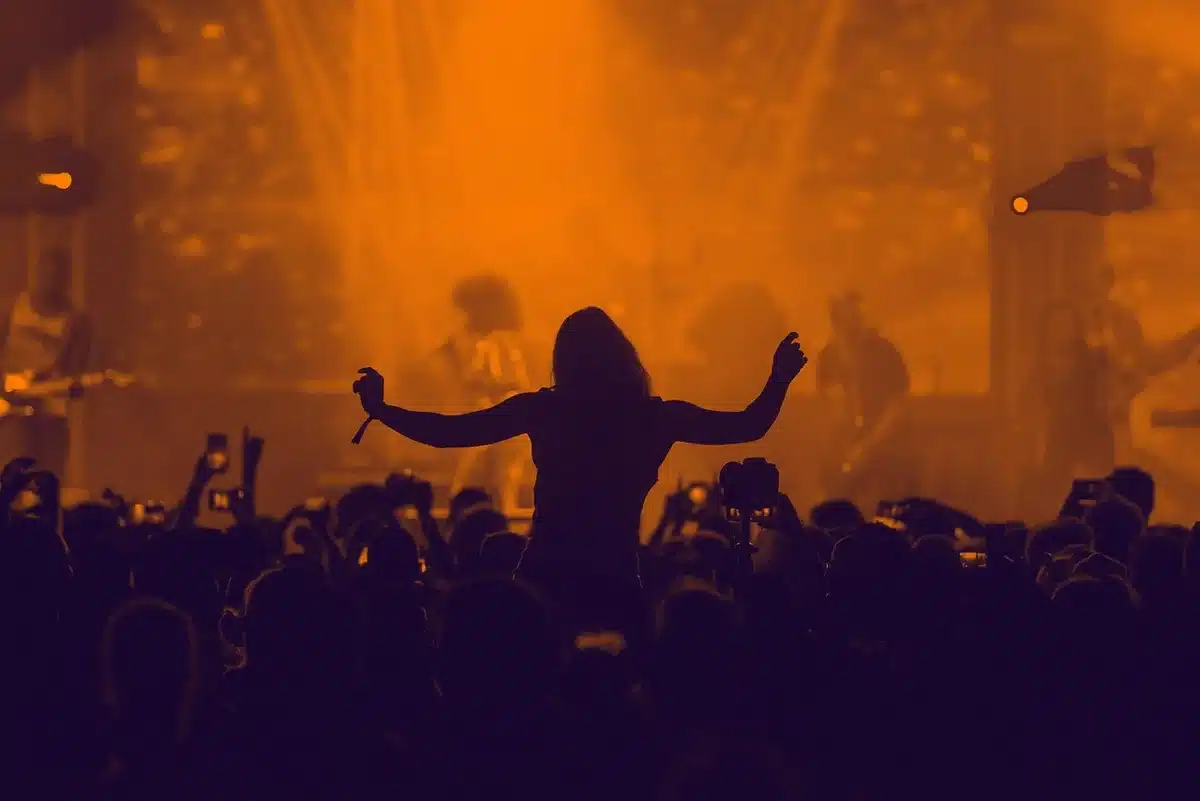 Due performer su un palco illuminato durante un momento di interazione inaspettata con luci e atmosfera di grande evento