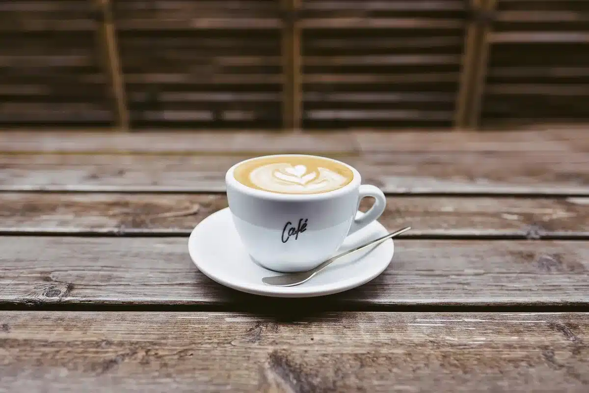 Mani anonime che sfogliano un giornale su un tavolo da redazione con caffè