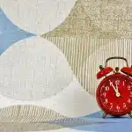 Mani anonime che tengono una pagina di calendario e un orologio da tavolo, simbolo di scadenza