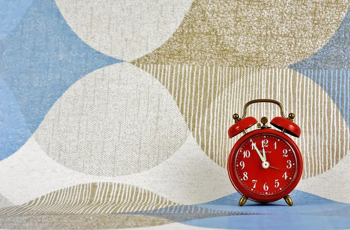 Mani anonime che tengono una pagina di calendario e un orologio da tavolo, simbolo di scadenza