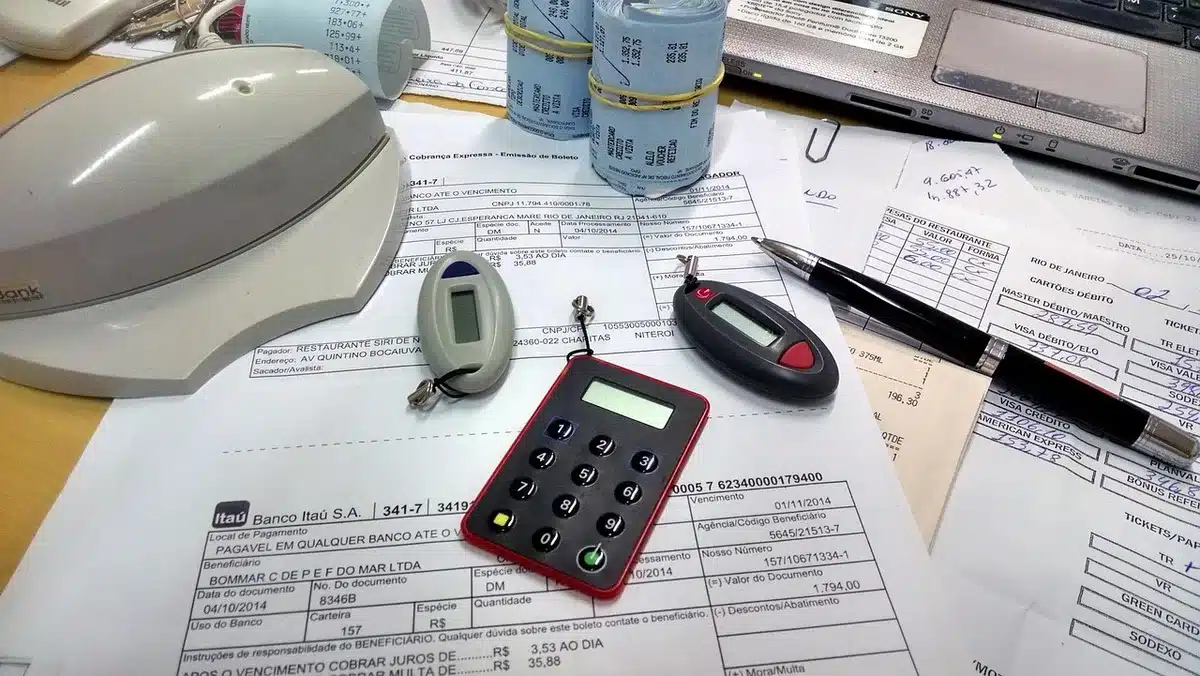 Mani che consultano documenti contributivi e una calcolatrice sulla scrivania